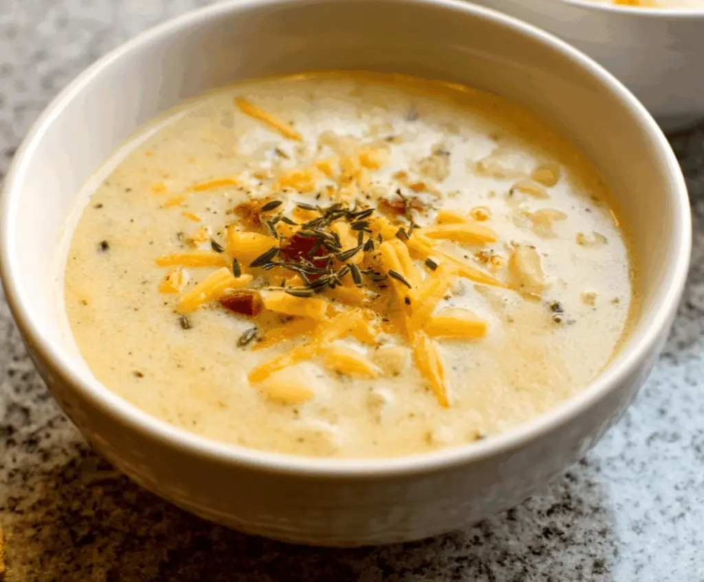 Creamy cheddar garlic herb potato soup in a bowl topped with fresh herbs and melted cheese, perfect for cozy meals.