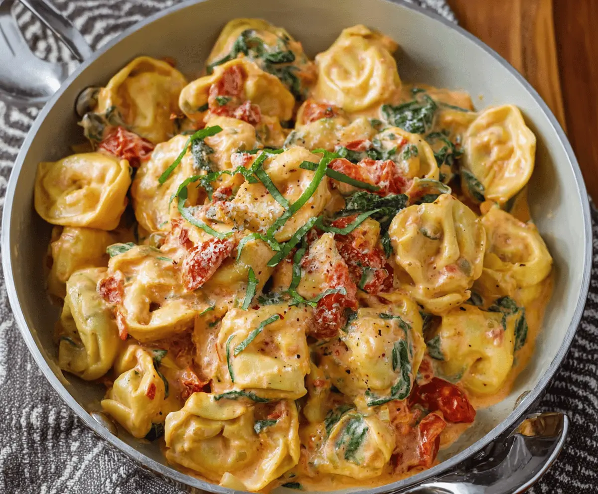 Creamy spinach and tomato tortellini served in a white bowl with fresh basil garnish, showcasing a delicious and easy pasta recipe.