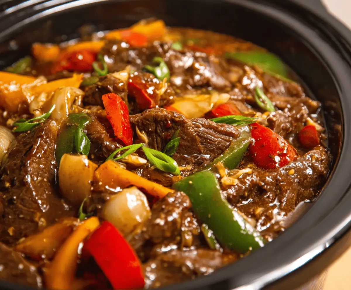 Tender pepper steak cooking in a crock pot with colorful bell peppers and onions, ready to serve