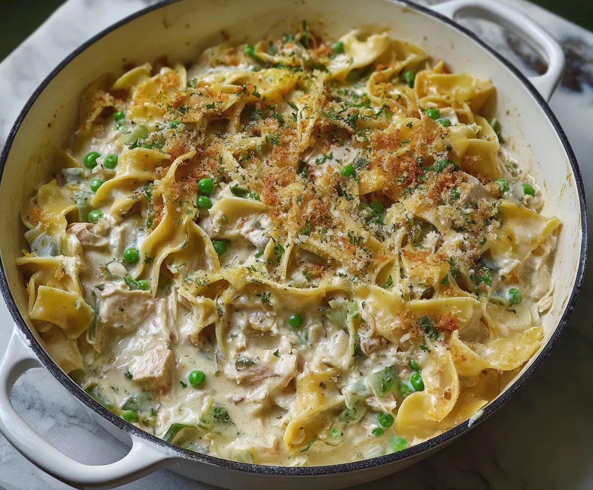 Delicious creamy tuna noodle casserole topped with melted cheese and fresh herbs.