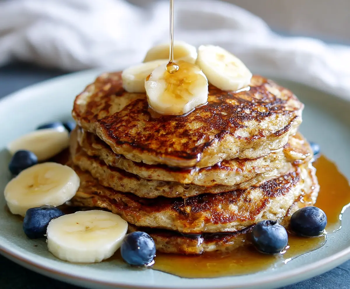 Easy 3 Ingredient Banana Oatmeal Pancakes served on a plate with fresh fruits.