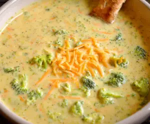 Creamy and healthy broccoli cheddar soup in a bowl, garnished with fresh herbs.
