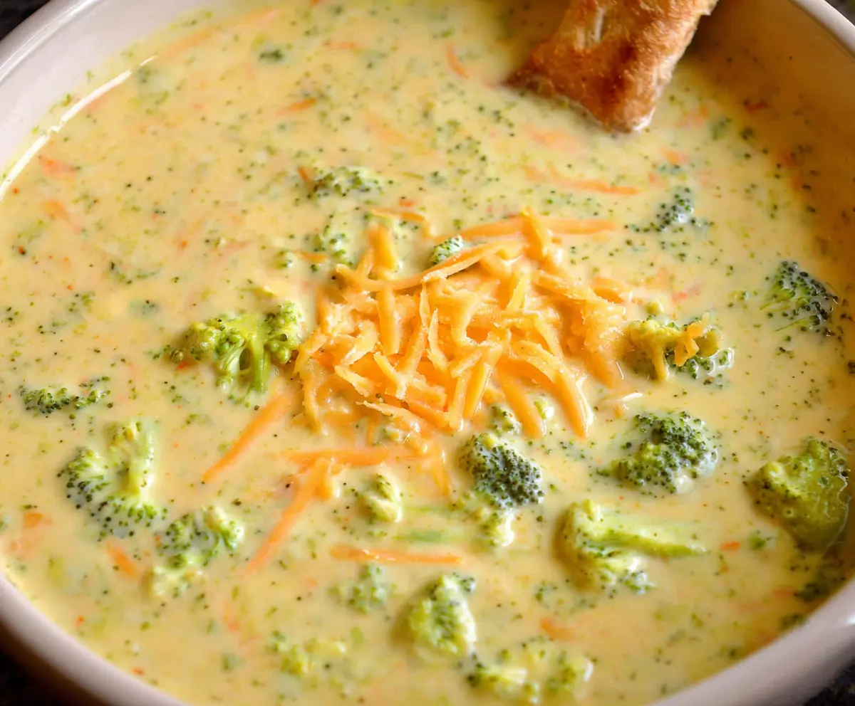 Creamy and healthy broccoli cheddar soup in a bowl, garnished with fresh herbs.