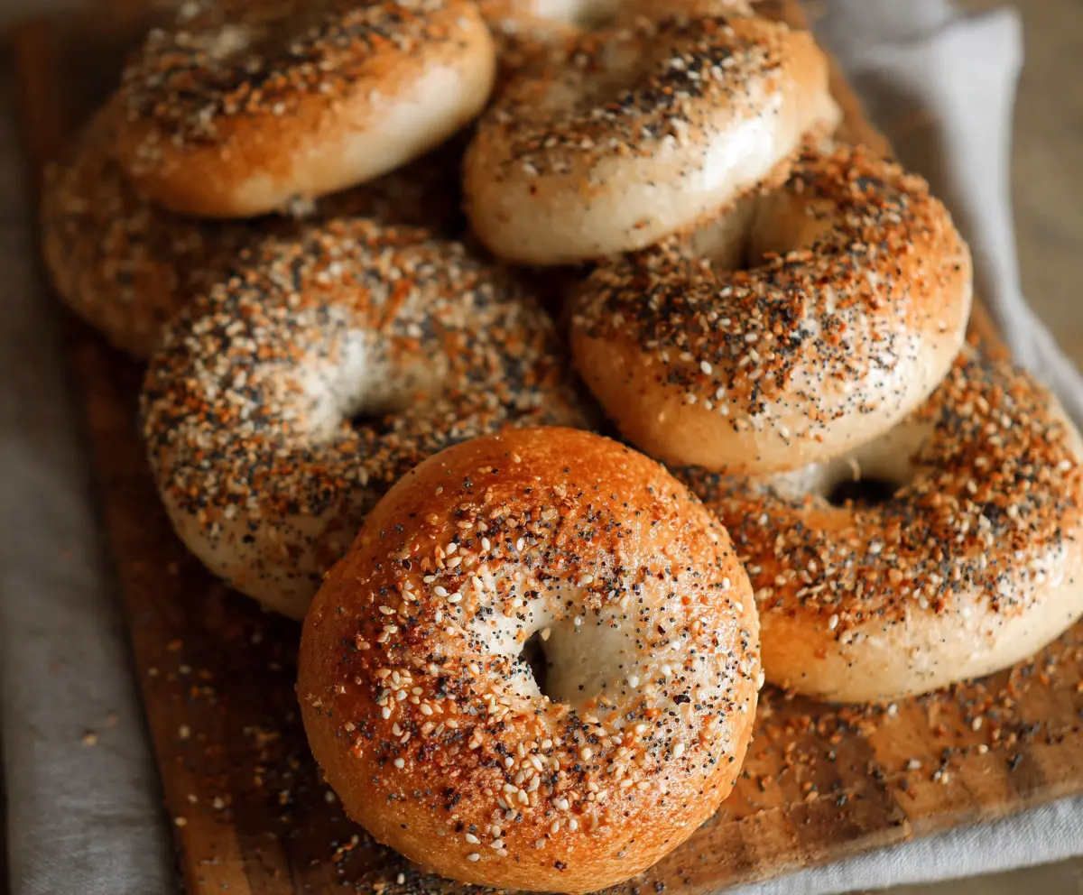 Freshly baked sourdough bagels on a wooden cutting board, showcasing their crispy crust and chewy interior.
